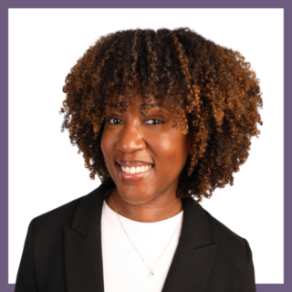 A person with curly hair smiles at the camera. They are wearing a black blazer over a white shirt and a small necklace. The background is white with a purple border.