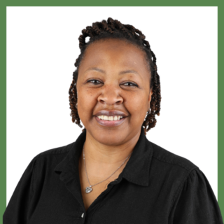 A person with braided hair is smiling, wearing a black shirt and a necklace with a heart-shaped pendant. The background is white with a green border.