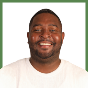 A man with short hair and a beard is smiling while wearing a white shirt. The background is white with a green border.