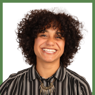 A person with curly hair smiles brightly, wearing a black and white striped shirt and a statement necklace with a geometric pendant. A green border frames the image.