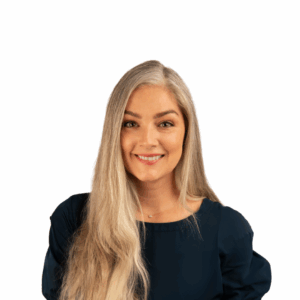 A woman with long, straight, light blonde hair and fair skin smiles at the camera. She is wearing a dark navy top and is posed against a plain white background.