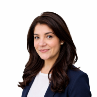 A woman with long, wavy brown hair wearing a navy blazer and white top smiles softly at the camera against a plain white background.