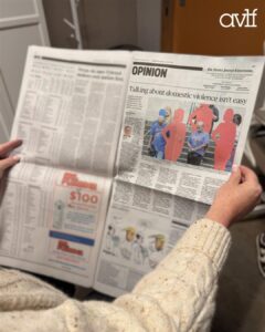 A person wearing a cream sweater holds a newspaper opened to an opinion article titled