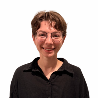 A person with short brown hair, wearing round glasses and a black collared shirt, is smiling against a plain white background.