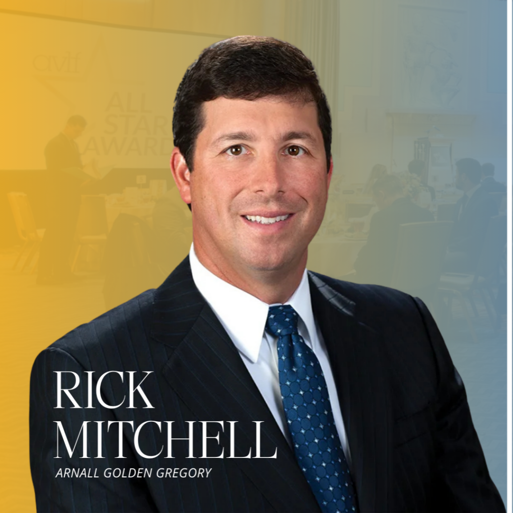 A man in a dark pinstripe suit and blue tie smiles at the camera. Text reads "Rick Mitchell, Arnall Golden Gregory." The background has a yellow and blue gradient with faint images of people at an event.